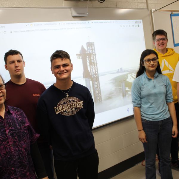  students with image of a rocket ship in the background