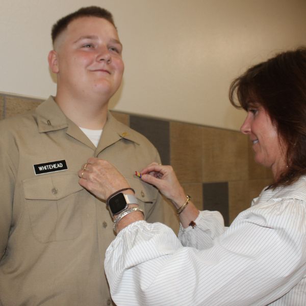  Woman pinning military ribbon on student's uniform