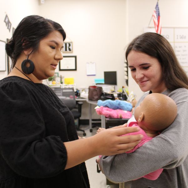  Teacher speaking with student holding baby simulator