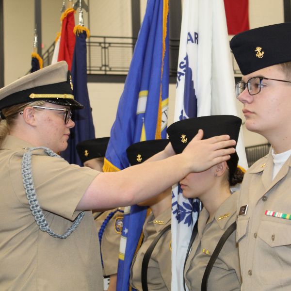  Female Commanding Officer in CHS Navy Defense Cadet Corps straightens the cap of a cadet during uni