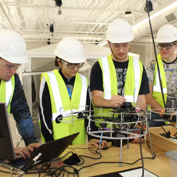  Students in hard hats around a drone